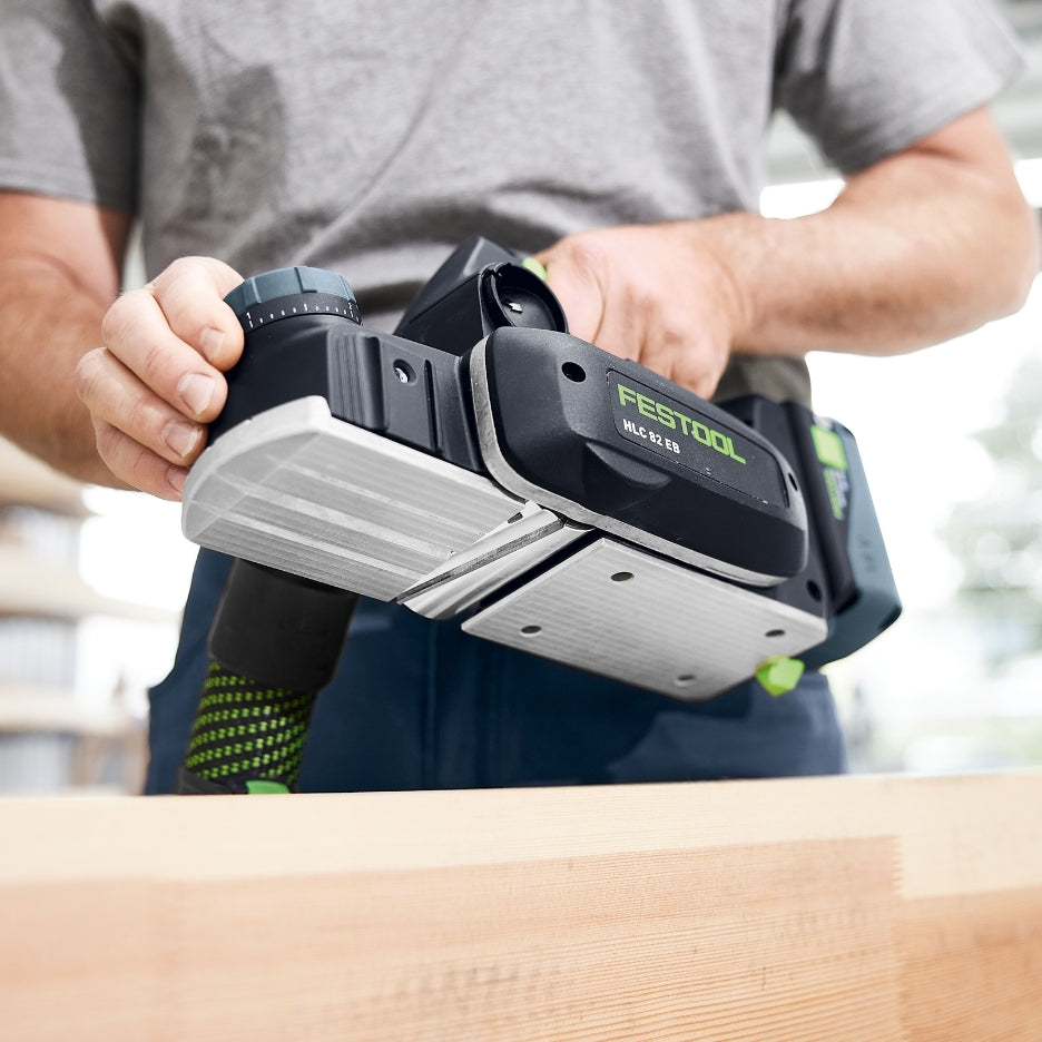A close-up view of a Festool HLC 82 EB cordless planer held in hand, showcasing its parallel side fence