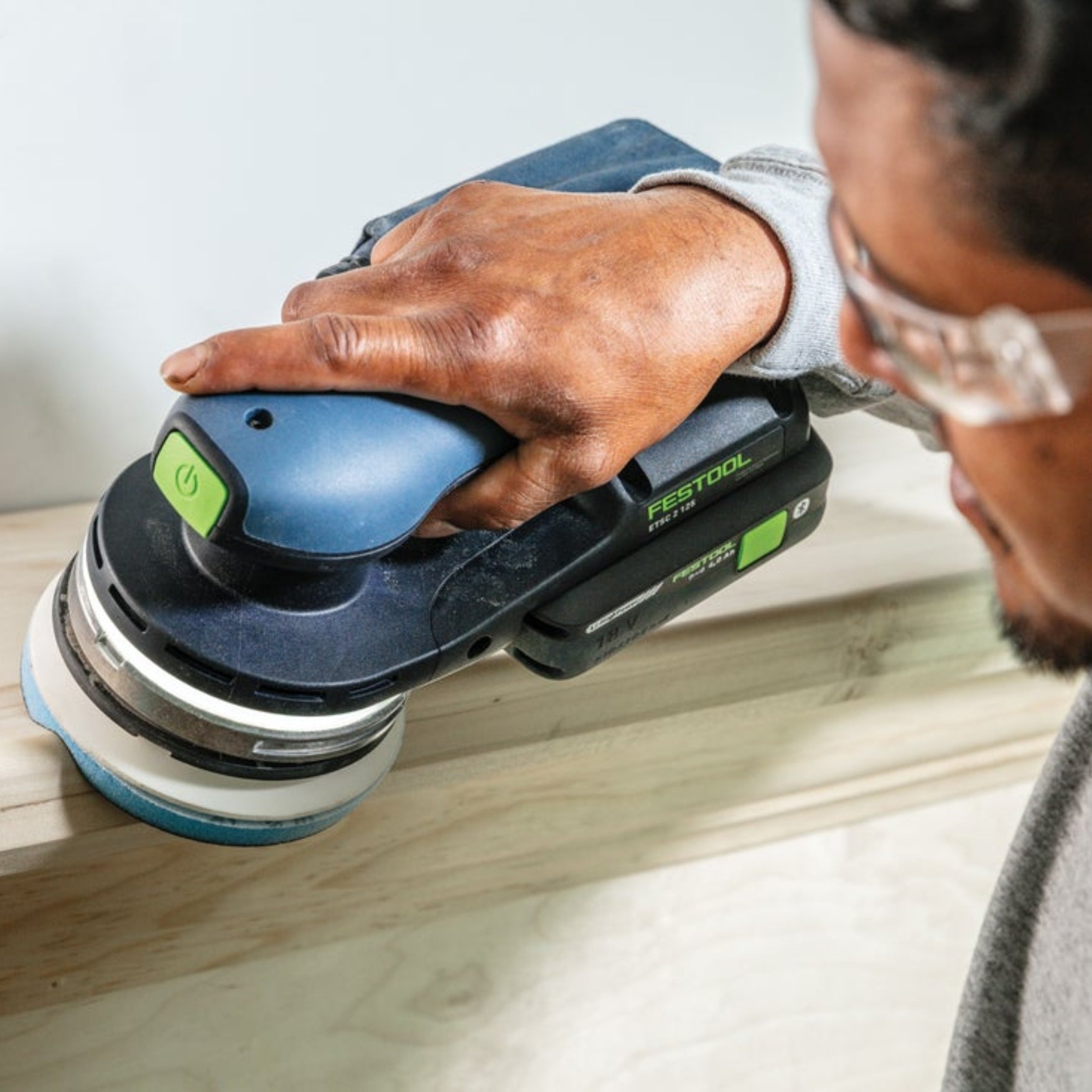 Close up at man using Festool sander with Festool Grit Abrasives Granat PROfile D125 M GR PRO to sand wooden mantel