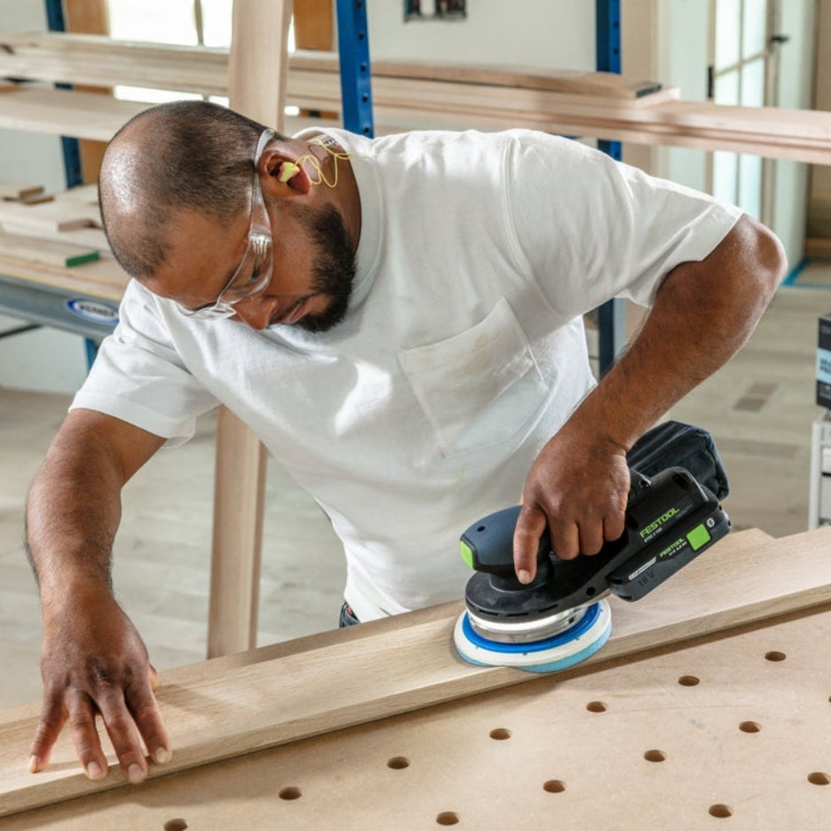 Man sanding a piece of wood using a Festool sander and Festool Grit Abrasives Granat PROfile D150 M GR PRO