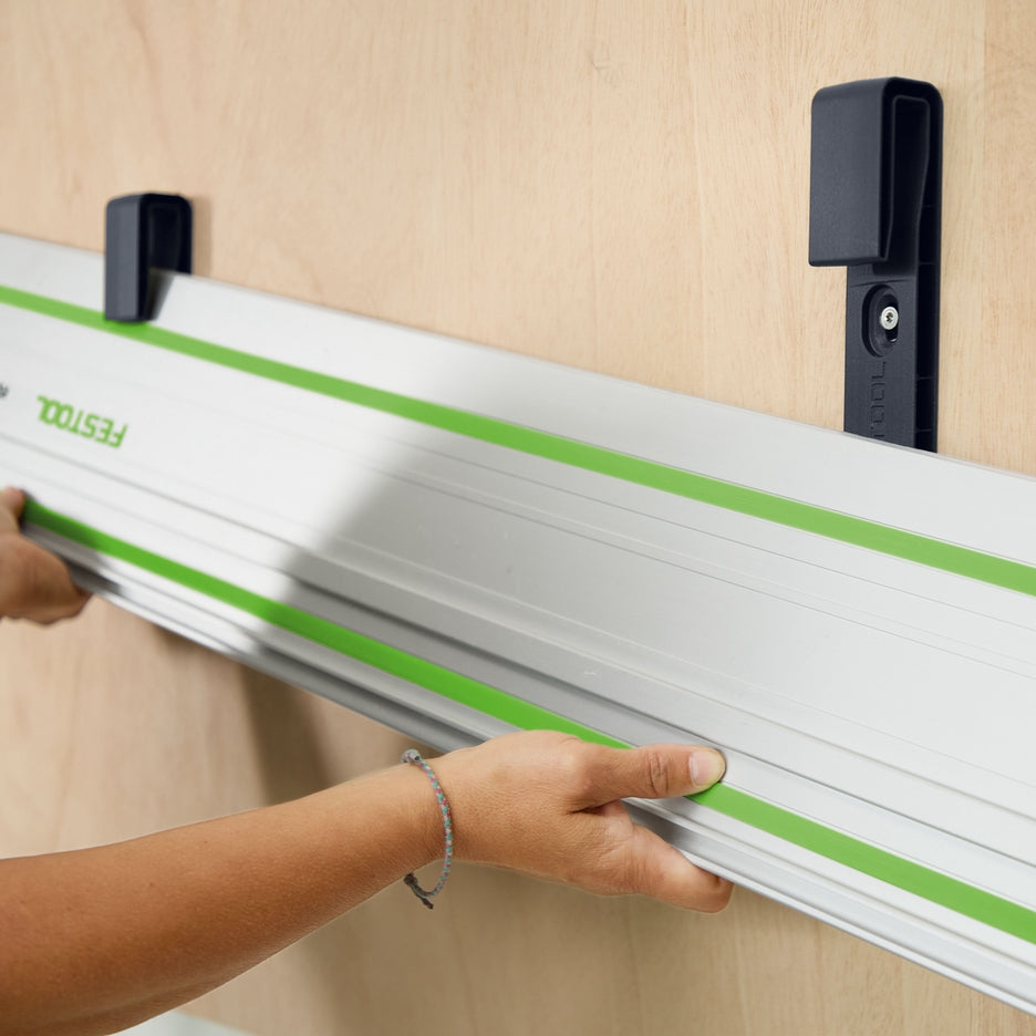 Person slides a Festool guide rail into the Guide Rail Holder Brackets mounted on a wall.