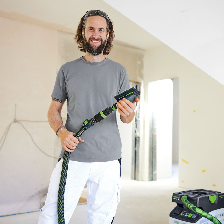 Painter smiles while holding Festool hand sanding block ready to sand drywall.