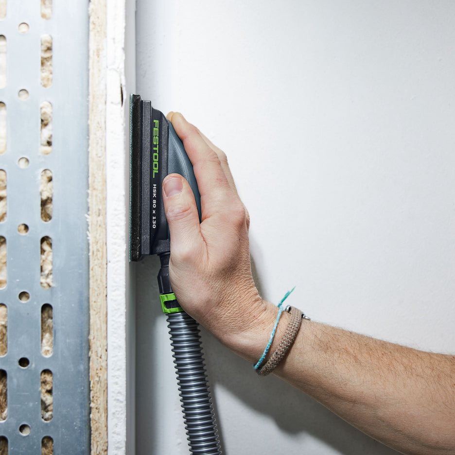 Man sands narrow drywall surface, showing slim and ergonomic profile of Festool sanding block.