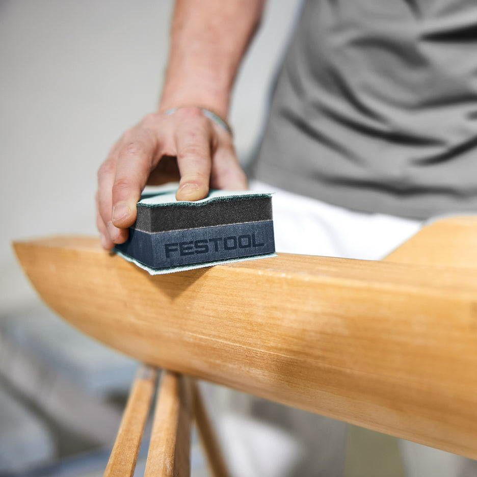 Man sands a flat wooden surface with Festool HSK-DUO foam sanding block.