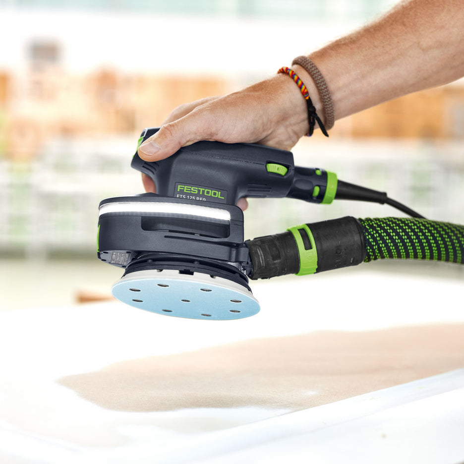 Man holds Festool ETS 125 5" orbital sander with DTS Light Module installed and lit.