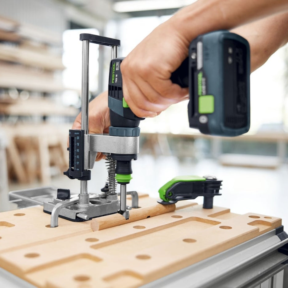 Hand using a cordless drill attached to Festool Mobile Drilling Attachment MB 40 on a multifunction table in a workshop setting