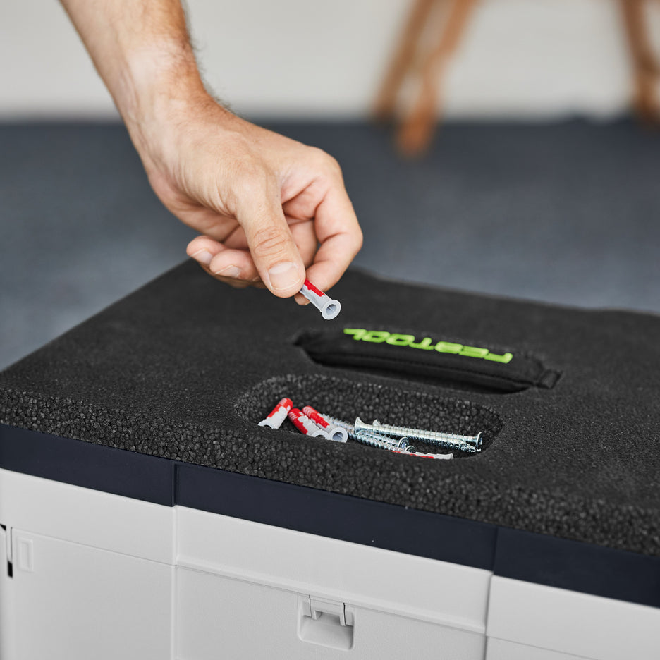 Man selects a hollow wall anchor from the small parts recess in the top of the Festool Seat Cushion.