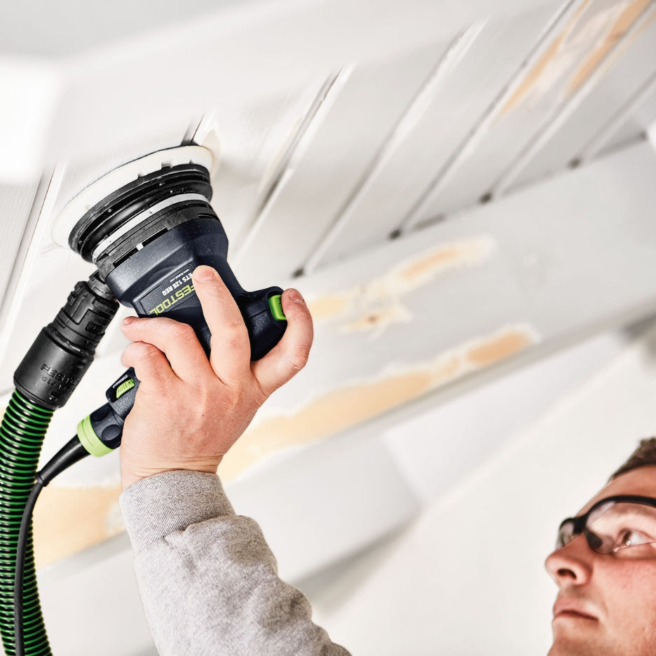Man using ETS 125 REQ Random Orbit Sander attached to Dust Extractor to sand a ceiling 