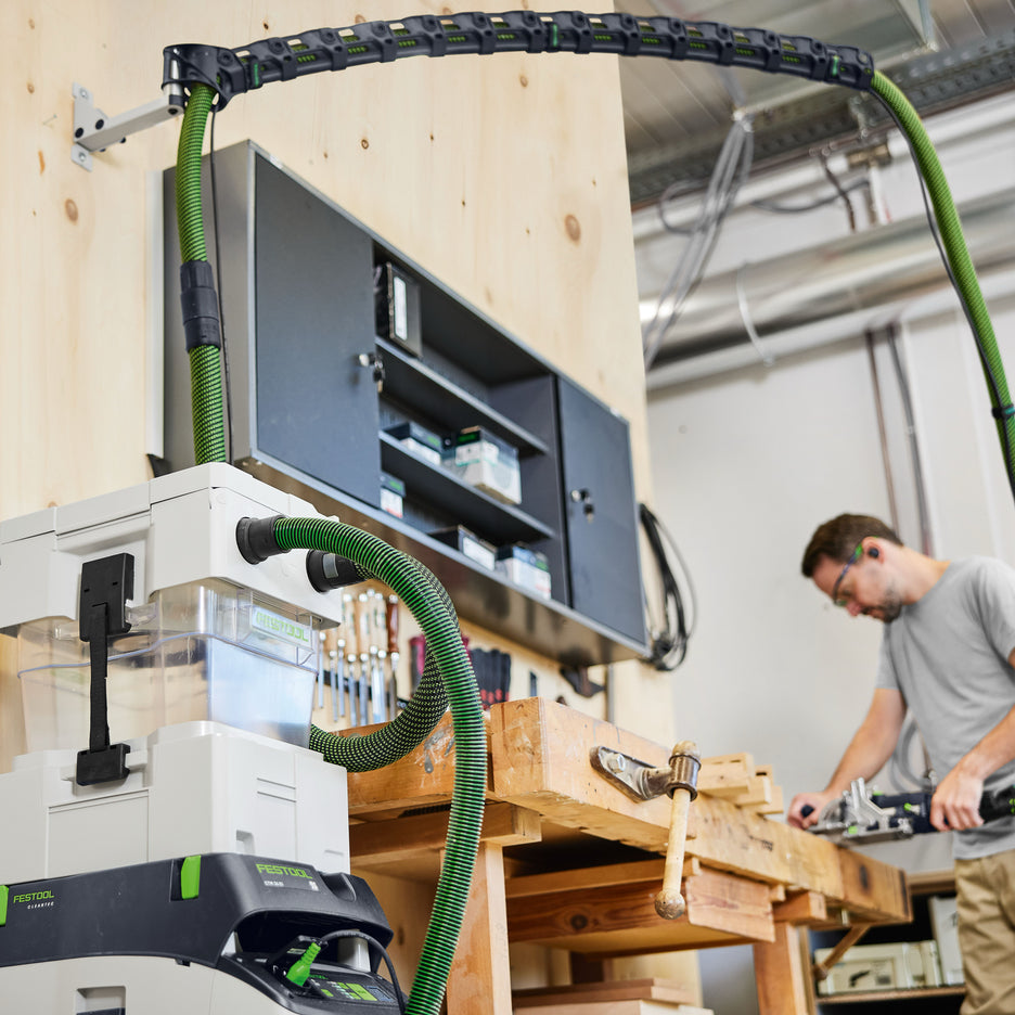 Low angle photo of Festool Wall-Mount Boom Arm Set connected to CT 36 dust extractor with CT Cyclone while man uses Domino to join wood.