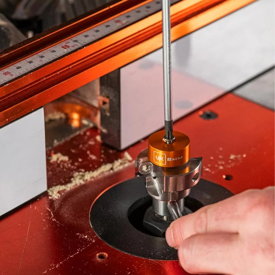 Close-up of a router with a person's hand adjusting the UJK Tools 2-Flute Metric Multi-Rabbetting Router Bit with 1/2 Inch Shank.