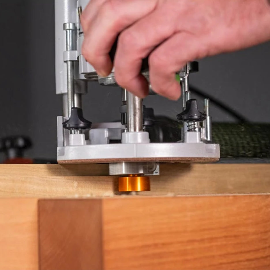 Hand operating a router table with a piece of wood on a blurred background