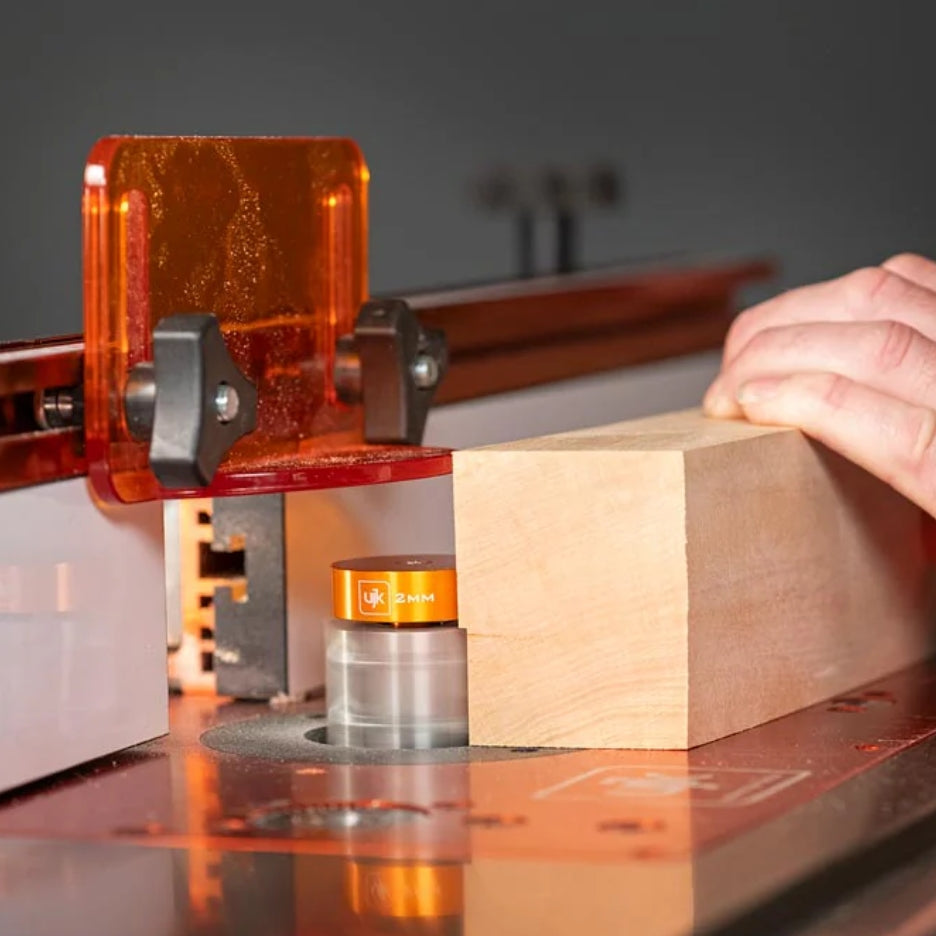 Router table with UJK Tools 3-Flute Metric Multi-Rabbetting Router Bit with 1/2 Inch Shank with a block of wood on a dark background
