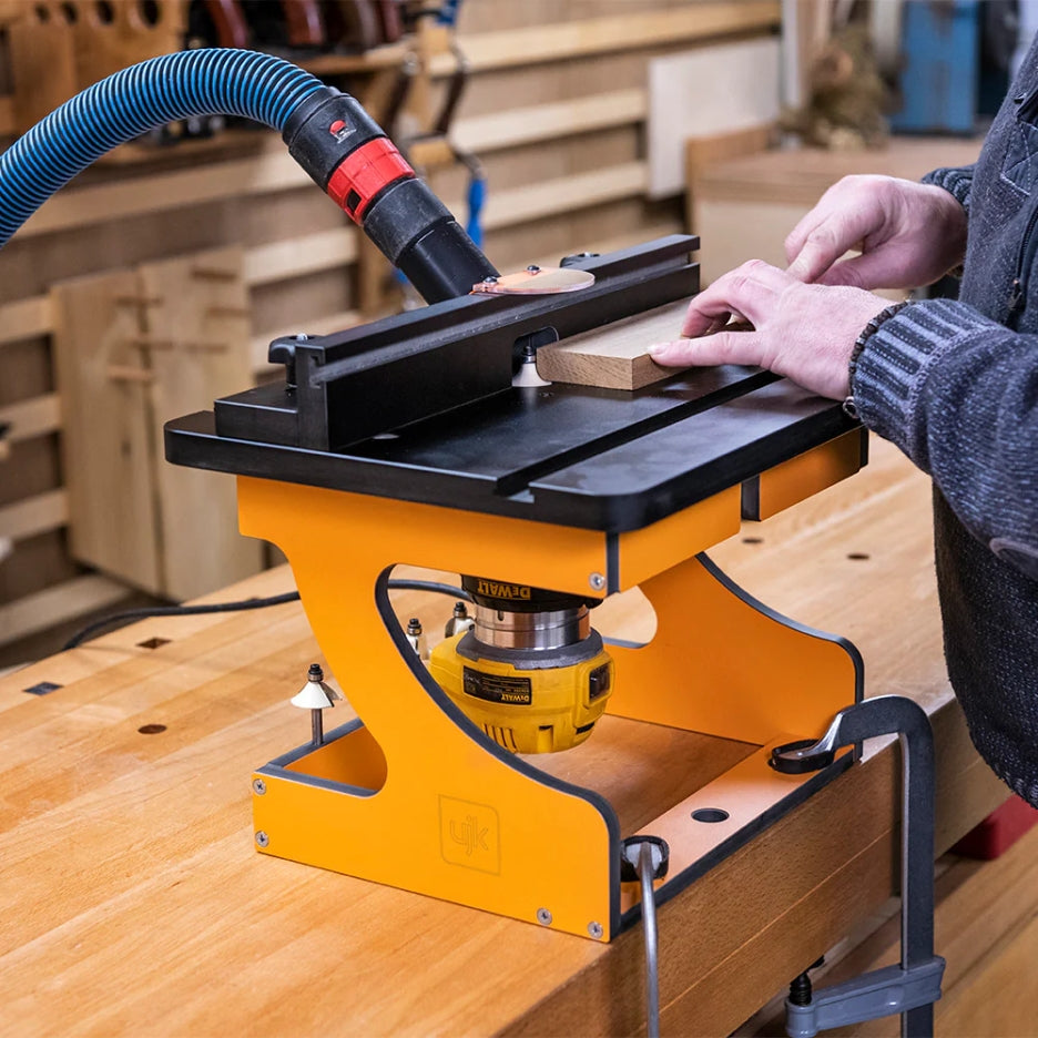 Person using UJK Tools Portable Trim Router Table attached to a dust extractor hose in a workshop setting.