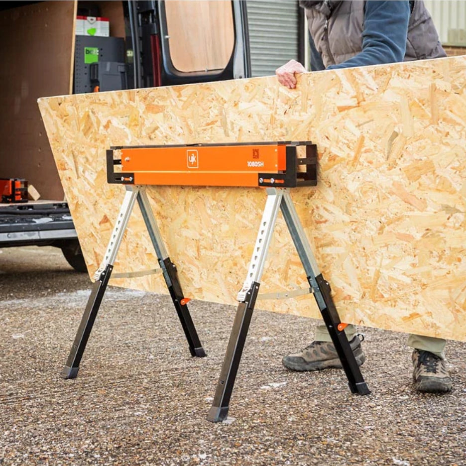 Person holding a large sheet of plywood with UJK Tools Sawhorses in front of a van.