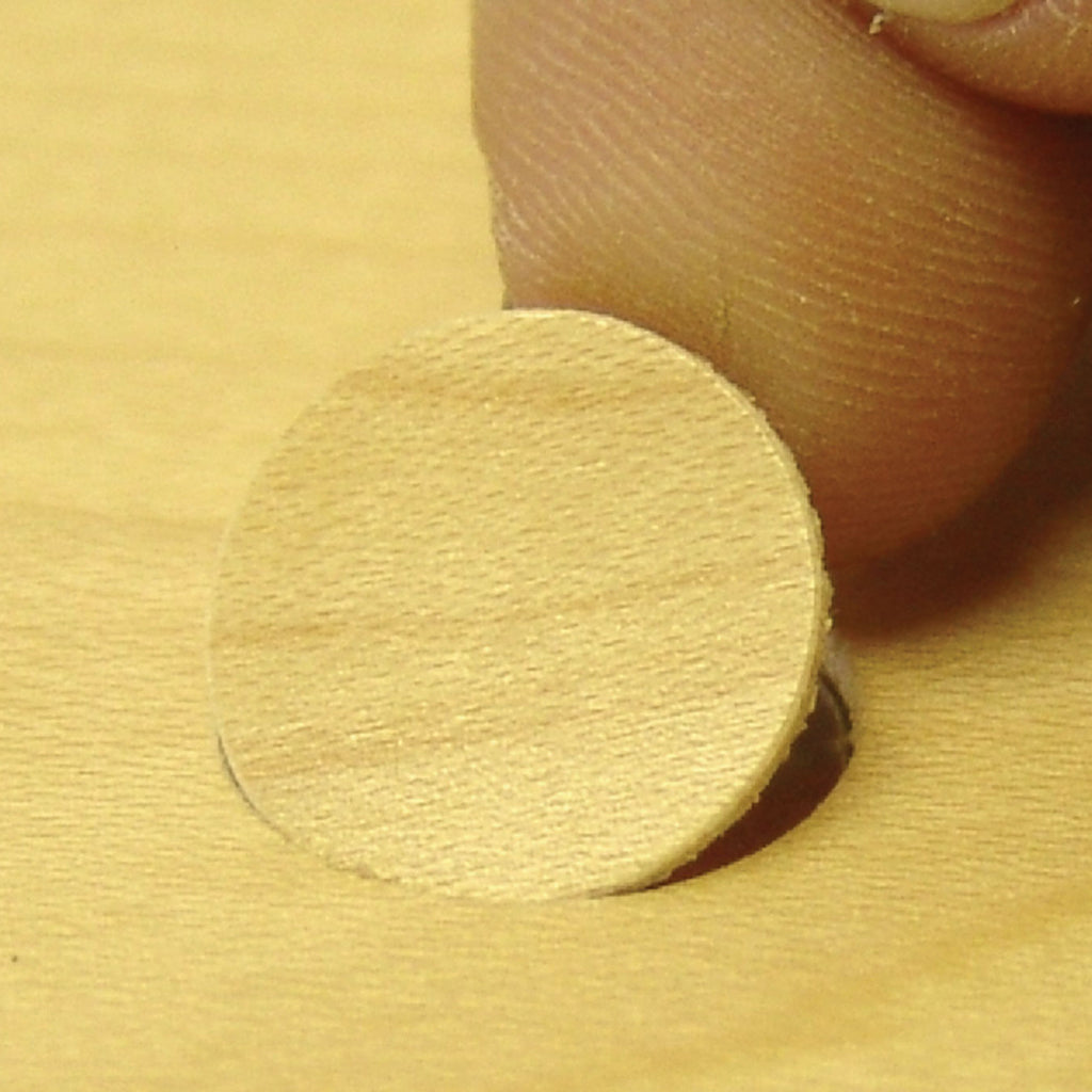 A custom-made screw cover is carefully positioned with a fingertip to hide the screw.