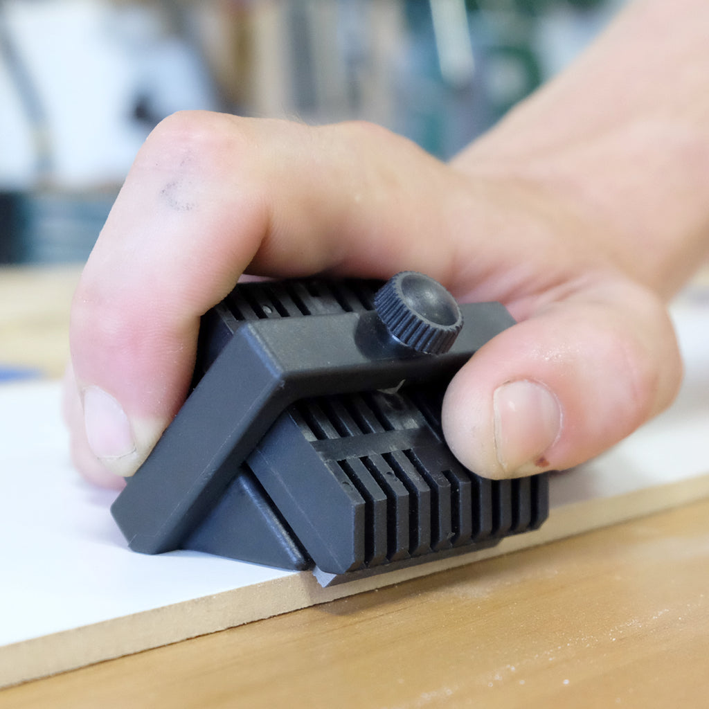 An operator pushes his Fast Break along the edge of a sheet of solid surface material sitting on a workbench.