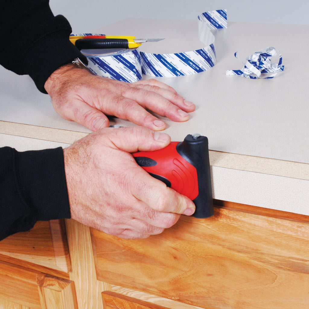 A worker uses FastCap's SpeedRoller Pro to apply a laminate edge to a countertop with SpeedTape.