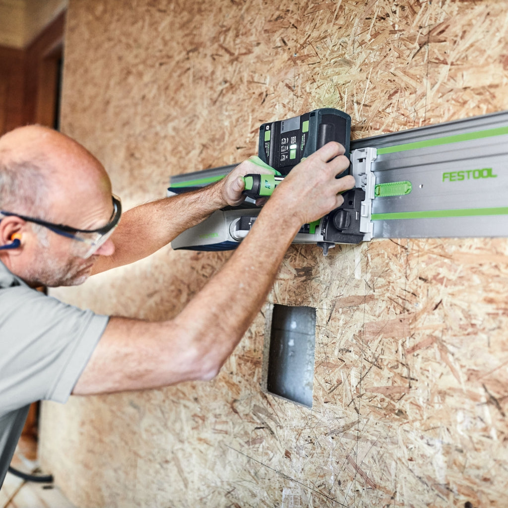 A carpenter uses removable adhesive pads to secure a Festool FS/2-KP guide rail to OSB wall panelling to make a straight cut.