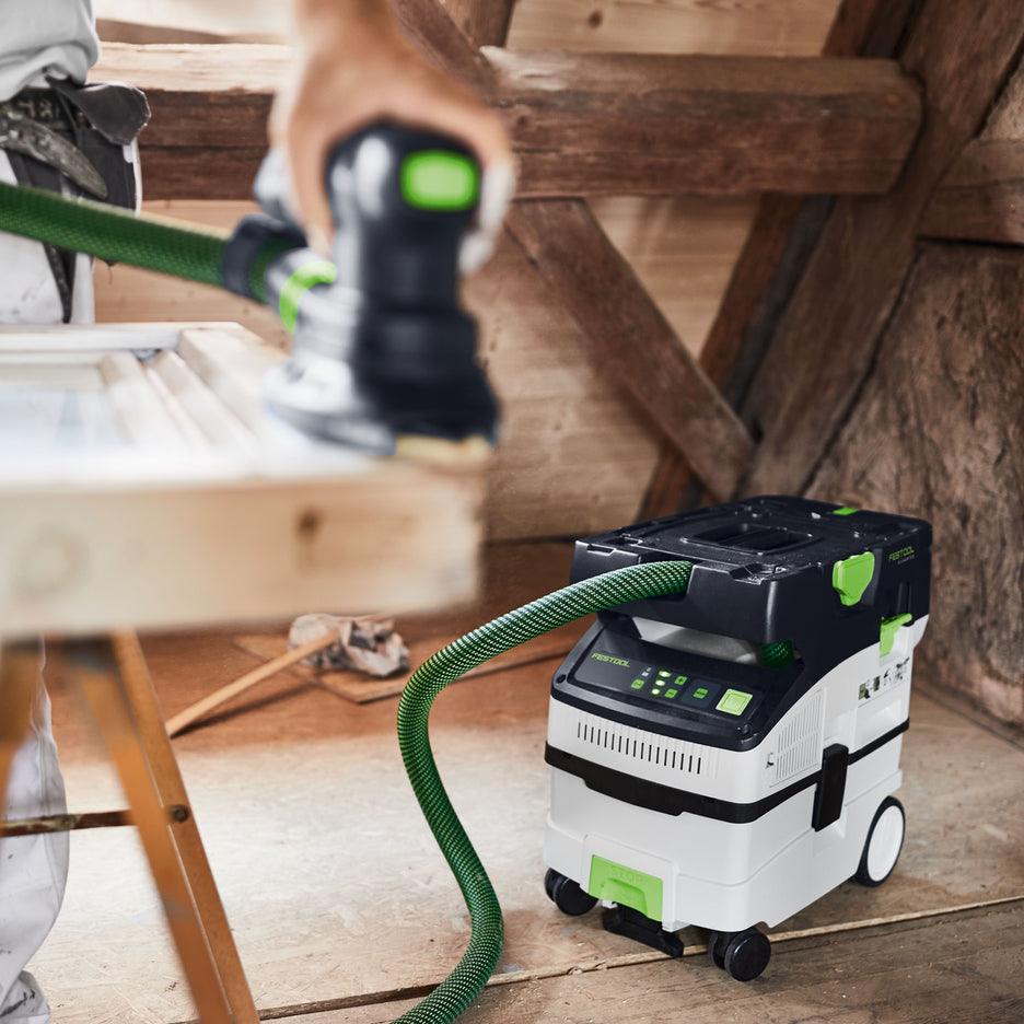 Worker uses a Festool CTC MIDI I Dust Extractor connected to cordless detail sander to sand a wooden window frame.