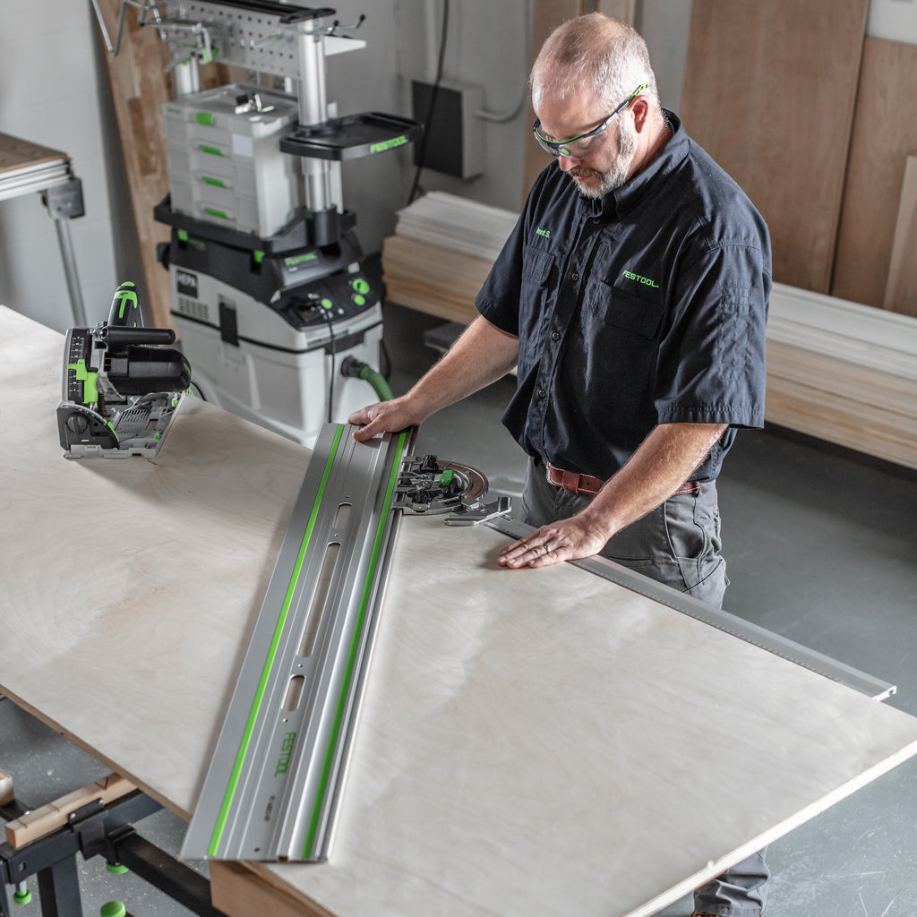 A cabinetmaker uses the Angle Stop w/extension to position a guide rail across a sheet of plywood for a mitre cut.