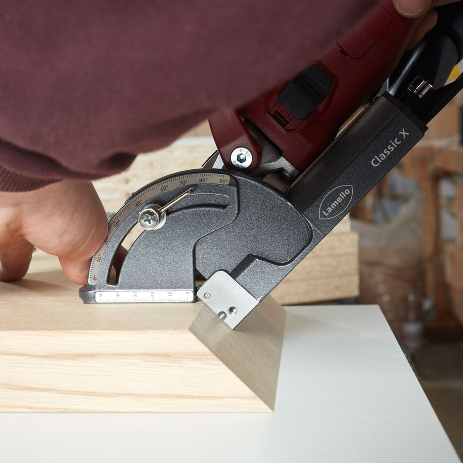 Woodworker positions Lamello Classic X Cordless Biscuit Joiner against mitred surface to cut slot.