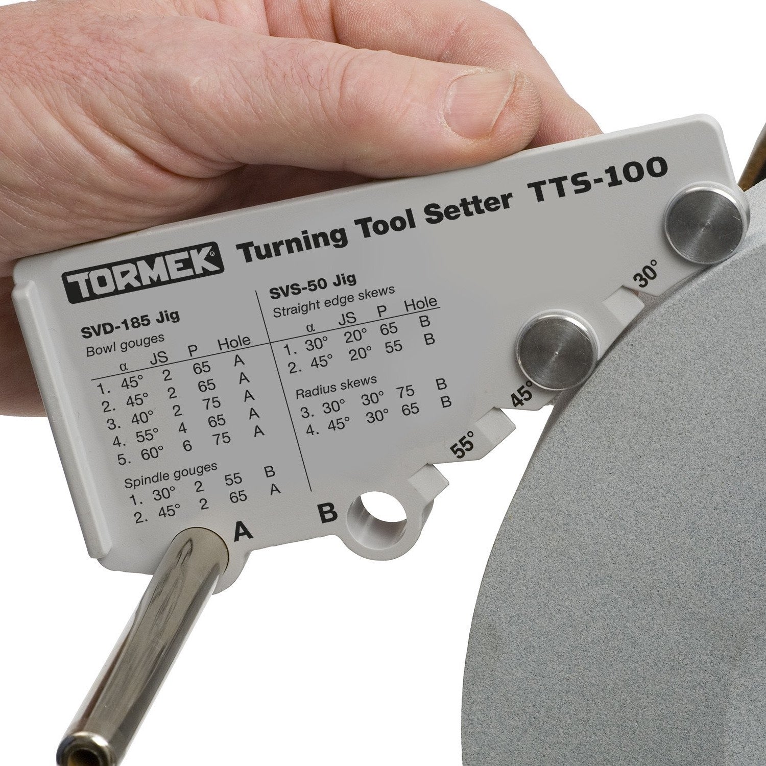 Tormek TTS-100 Turning Tool Setter Jig installed on steel jig guide bar against grinding wheel to set angle.