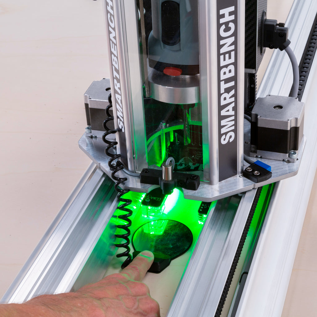 An operator holds the Z probe plate under the cutter to zero the Z axis with the console's built-in software.